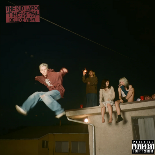 The Kid LAROI – The First Time (Deluxe Version) album cover: night rooftop scene with friends; parental advisory badge and Deluxe Vinyl sticker.