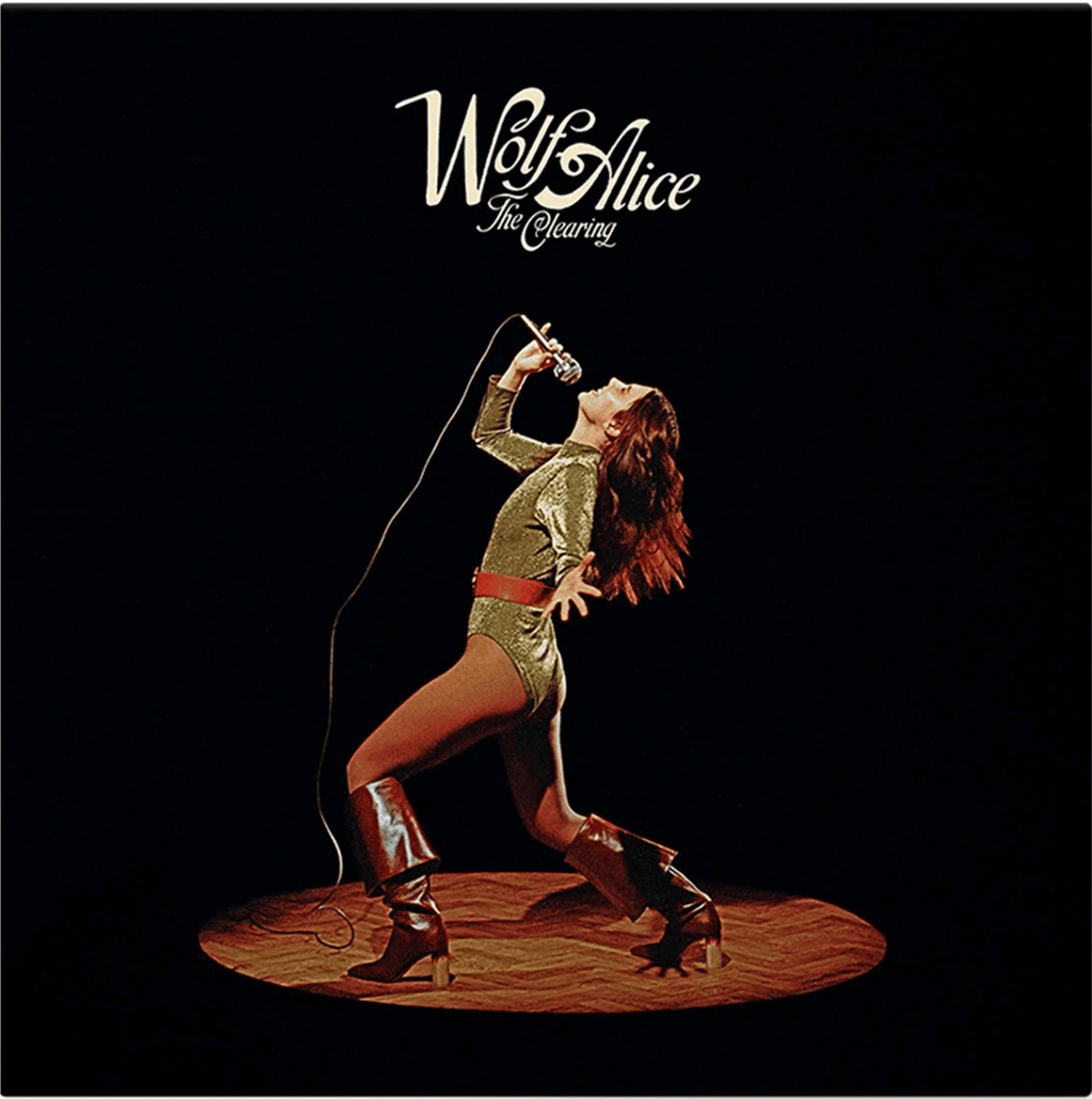 Album cover of The Clearing by Wolf Alice, featuring a retro-style photograph of a woman in a gold outfit and red boots singing into a microphone on stage under a spotlight, with the band’s name and album title in white script at the top.