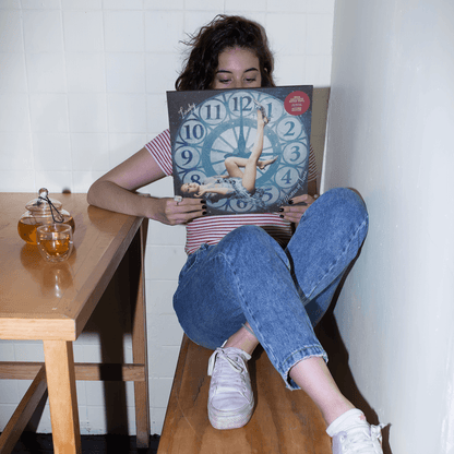 Person sitting at a dining table holding a copy of Laufeys new album; "A Matter of Time" on vinyl.  